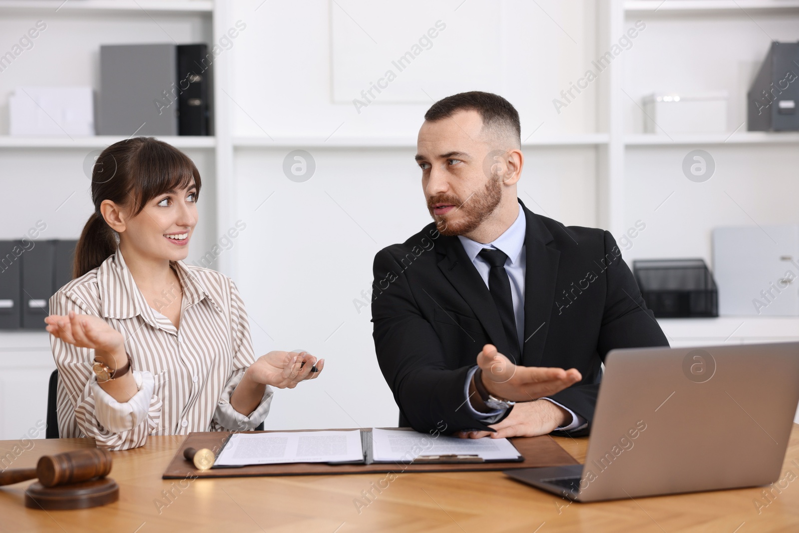 Photo of Woman having meeting with professional notary at wooden desk indoors