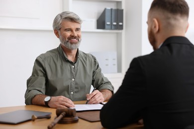 Photo of Man having meeting with professional lawyer at wooden desk indoors