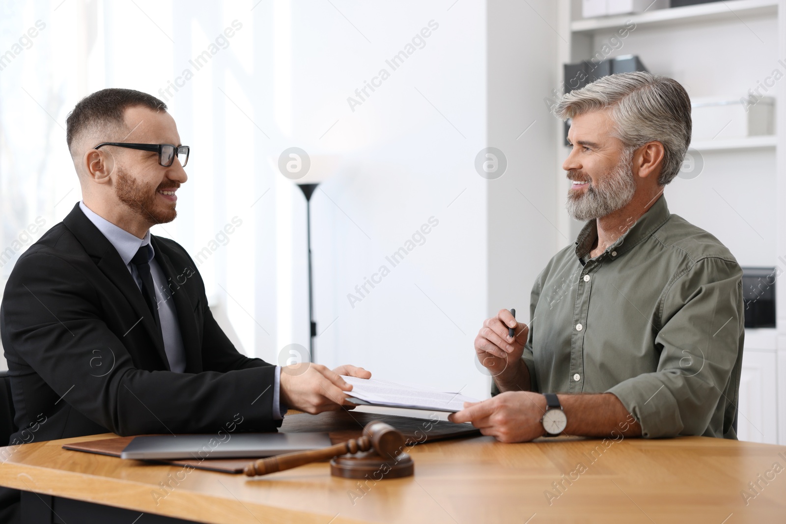 Photo of Man having meeting with professional lawyer at wooden desk indoors