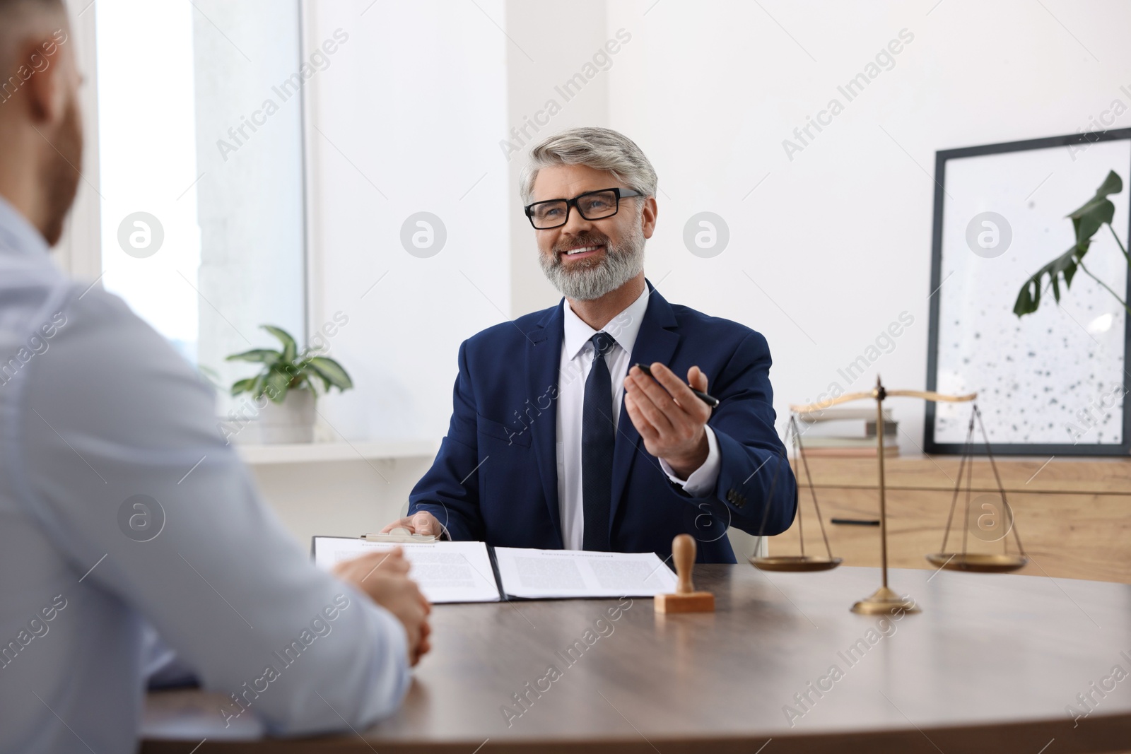 Photo of Man having meeting with professional lawyer at wooden desk indoors