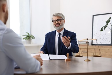 Man having meeting with professional lawyer at wooden desk indoors