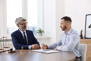 Photo of Man having meeting with professional lawyer at wooden desk indoors