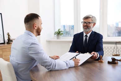 Photo of Man having meeting with professional lawyer at wooden desk indoors