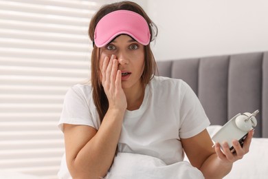 Overslept woman with alarm clock in bed at home