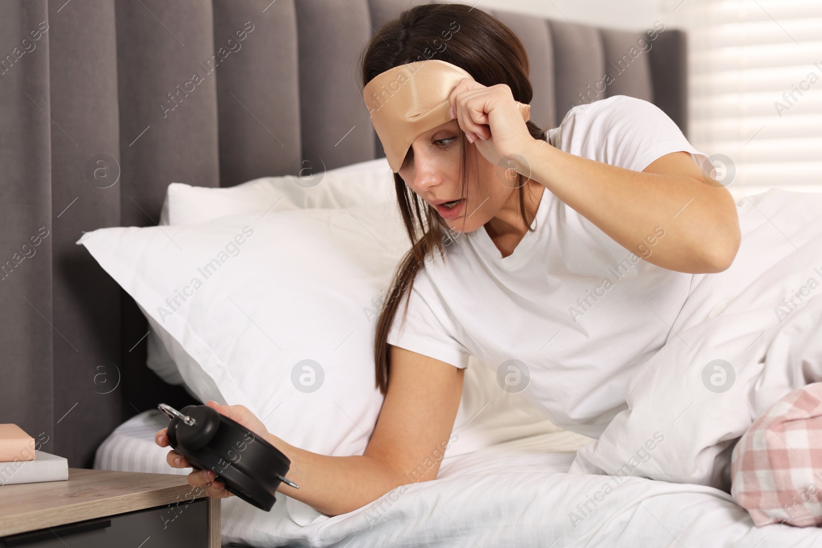 Photo of Overslept woman with alarm clock in bed at home