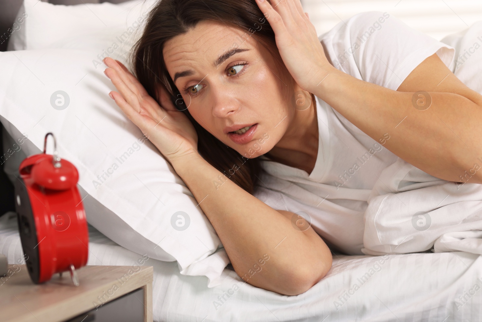 Photo of Overslept woman with alarm clock in bed at home