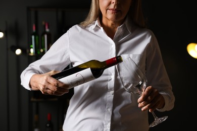 Photo of Professional sommelier pouring red wine into glass indoors, closeup