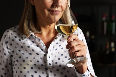 Photo of Professional sommelier tasting white wine indoors, closeup