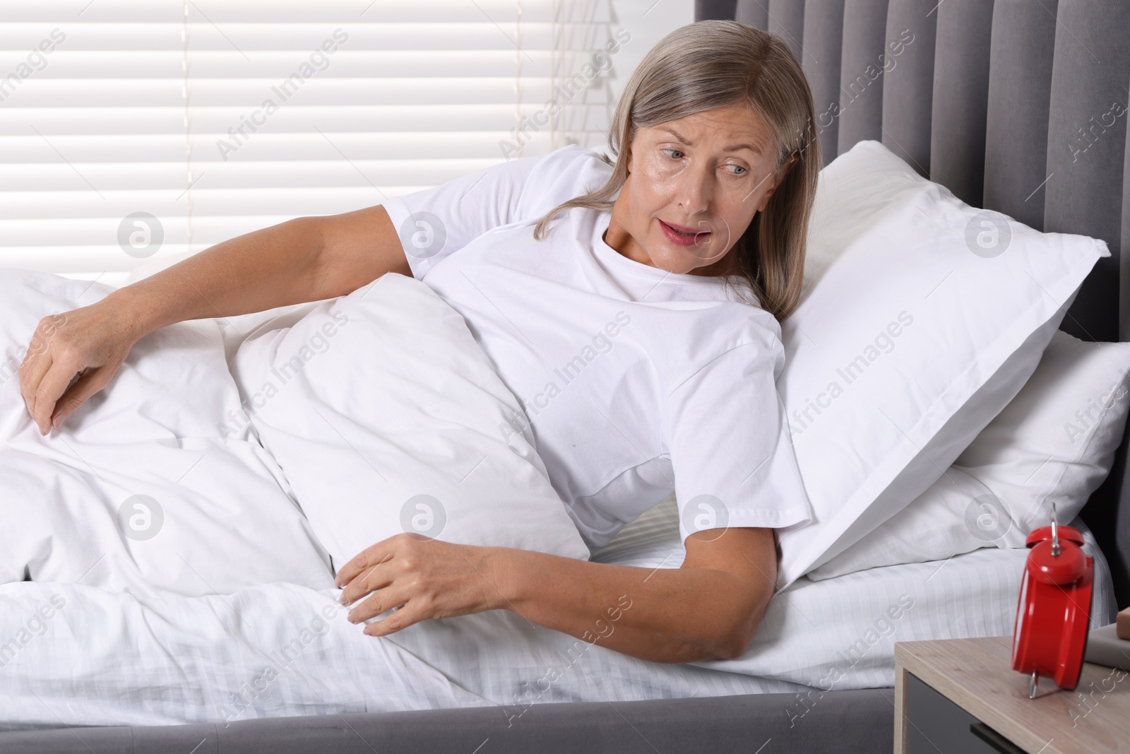 Photo of Overslept woman with alarm clock in bed at home