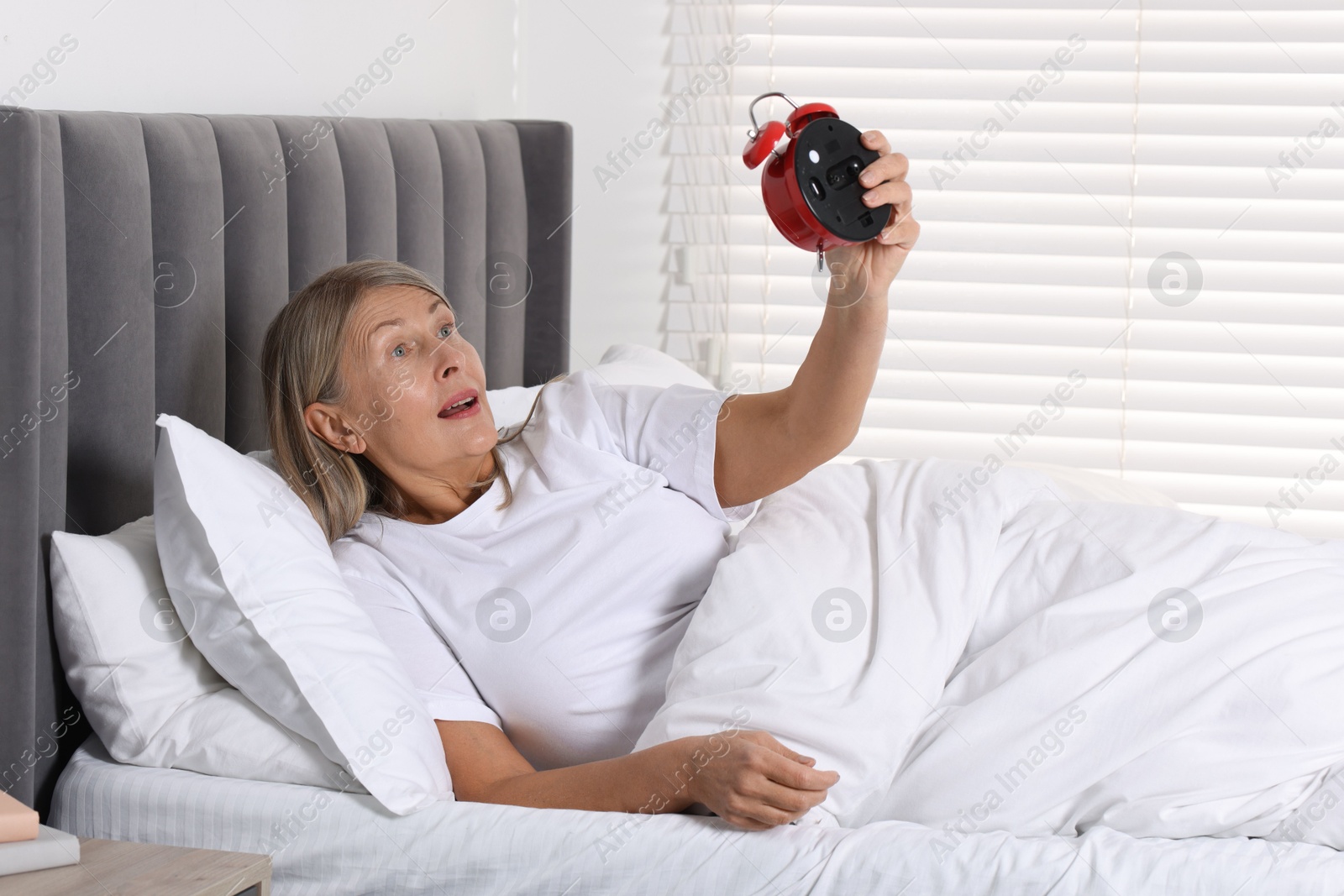 Photo of Overslept woman with alarm clock in bed at home