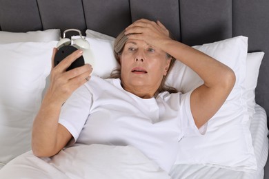 Photo of Overslept woman with alarm clock in bed at home