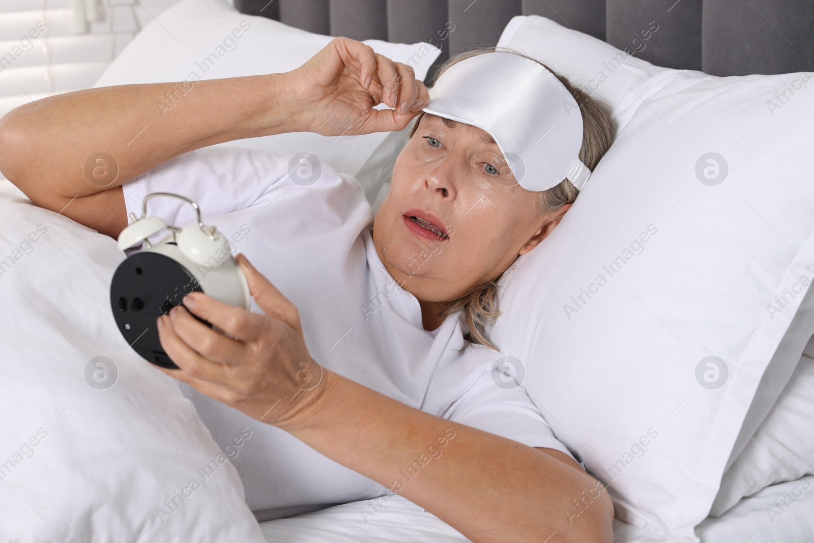 Photo of Overslept woman with alarm clock in bed at home