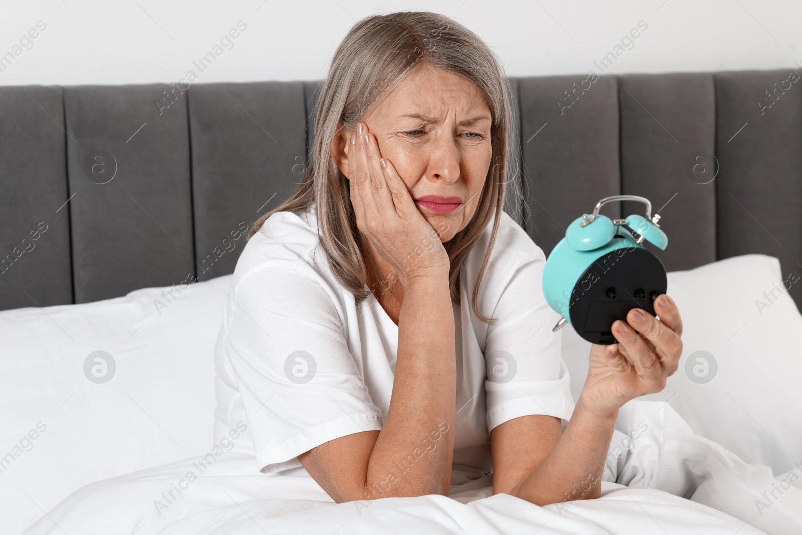 Photo of Overslept woman with alarm clock in bed at home