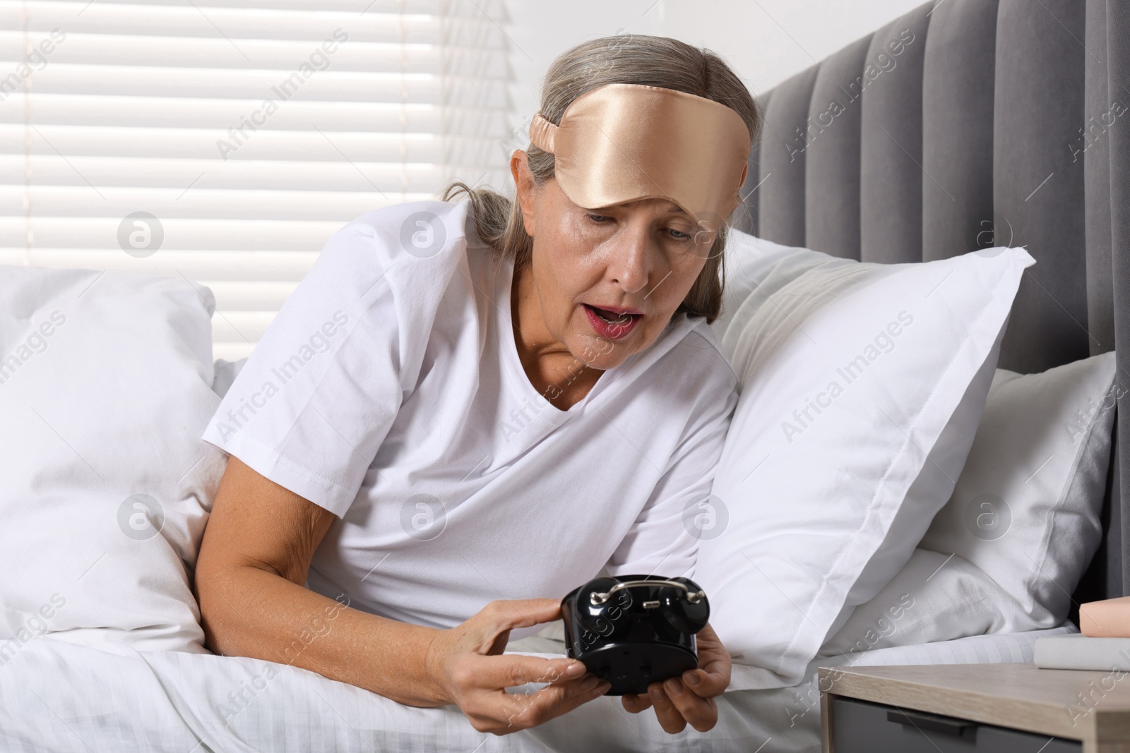 Photo of Overslept woman with alarm clock in bed at home