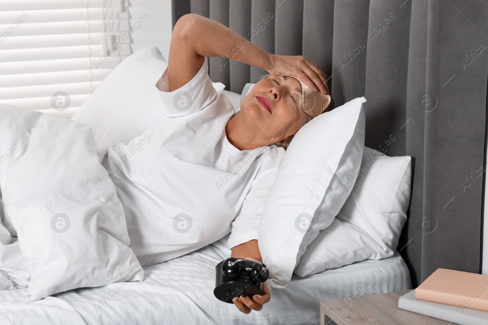 Photo of Overslept woman with alarm clock in bed at home