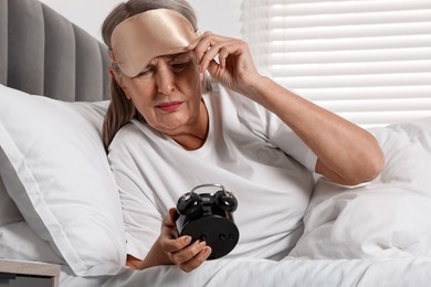 Photo of Overslept woman with alarm clock in bed at home