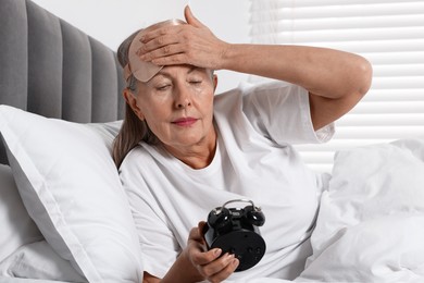 Photo of Overslept woman with alarm clock in bed at home