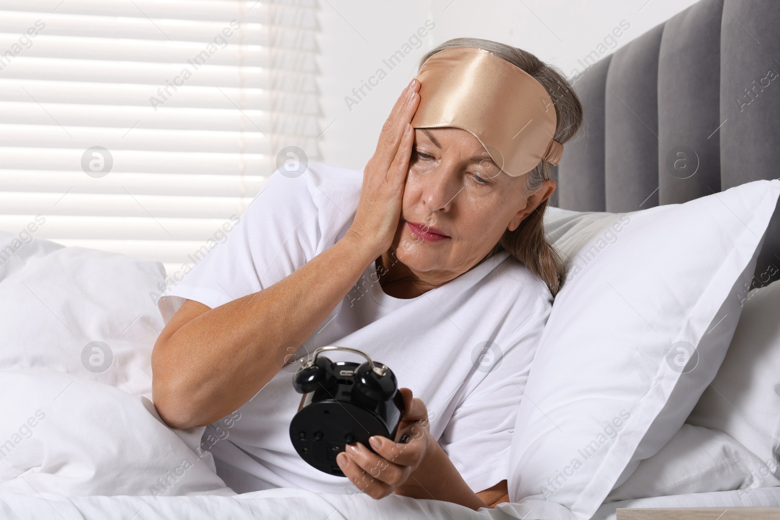 Photo of Overslept woman with alarm clock in bed at home