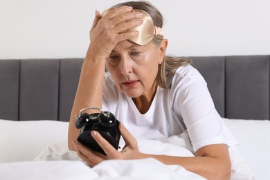 Photo of Overslept woman with alarm clock in bed at home