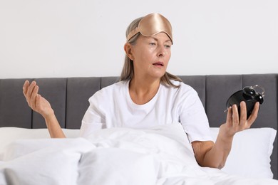 Photo of Overslept woman with alarm clock in bed at home