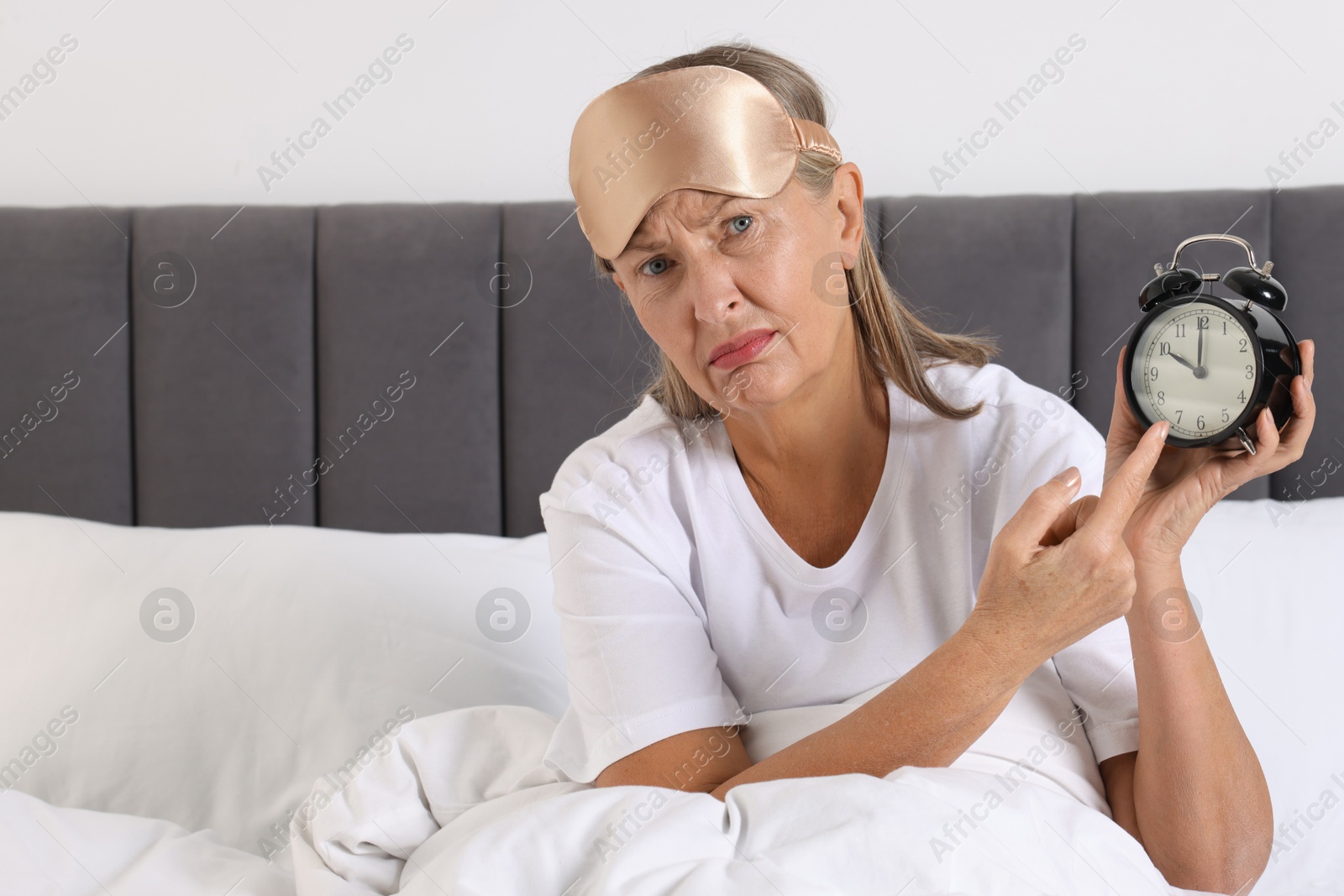 Photo of Overslept woman with alarm clock in bed at home