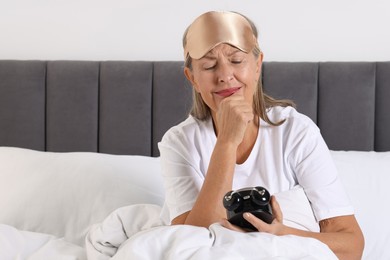 Photo of Overslept woman with alarm clock in bed at home