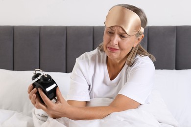 Photo of Overslept woman with alarm clock in bed at home