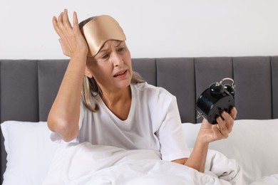 Photo of Overslept woman with alarm clock in bed at home