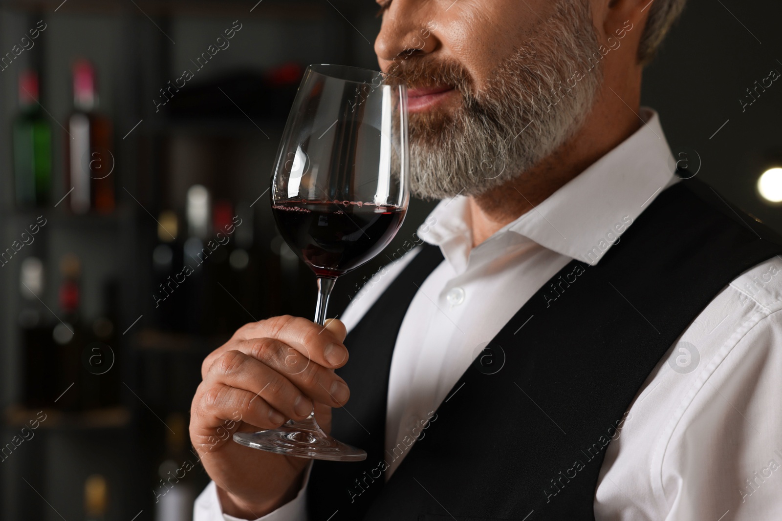 Photo of Professional sommelier tasting red wine indoors, closeup