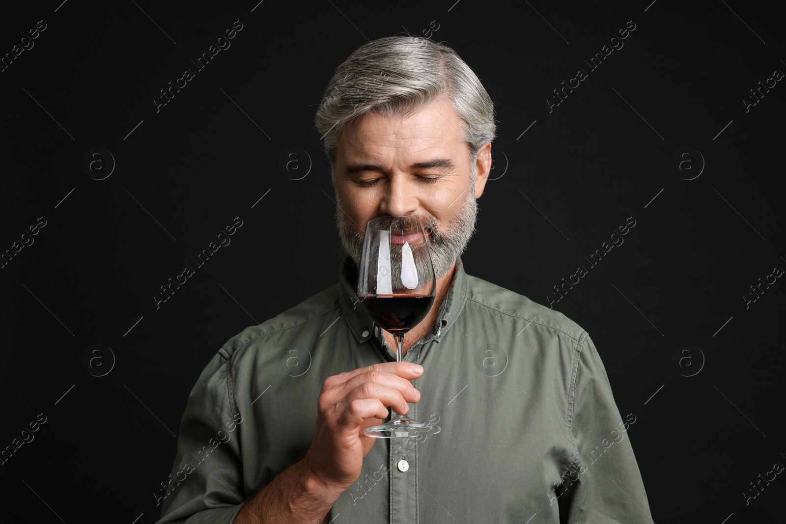 Photo of Professional sommelier tasting red wine on black background