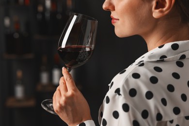 Photo of Professional sommelier tasting red wine in glass indoors, closeup