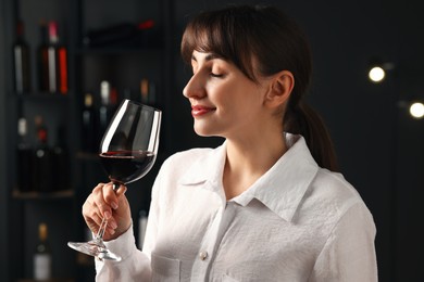 Photo of Professional sommelier tasting red wine in glass indoors