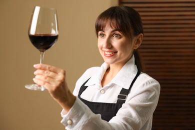 Photo of Professional sommelier analyzing quality of red wine indoors