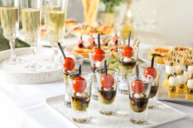 Photo of Many different tasty canapes and wine on white table, closeup