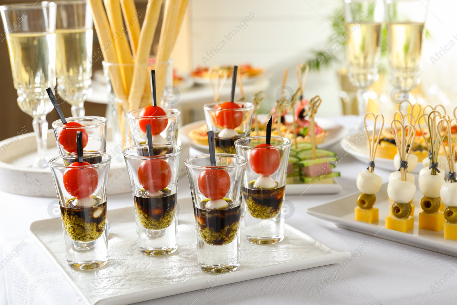 Photo of Many different tasty canapes and wine on white table