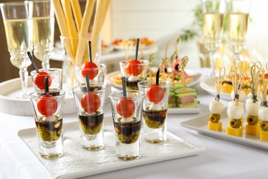 Photo of Many different tasty canapes and wine on white table