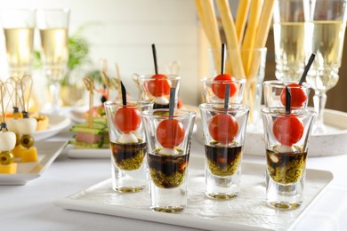 Photo of Many different tasty canapes and wine on white table