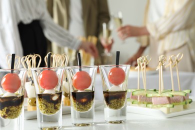 Photo of Many different tasty canapes on white table. People enjoying buffet meals indoors, closeup