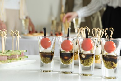 Photo of Many different tasty canapes on white table. People enjoying buffet meals indoors, closeup