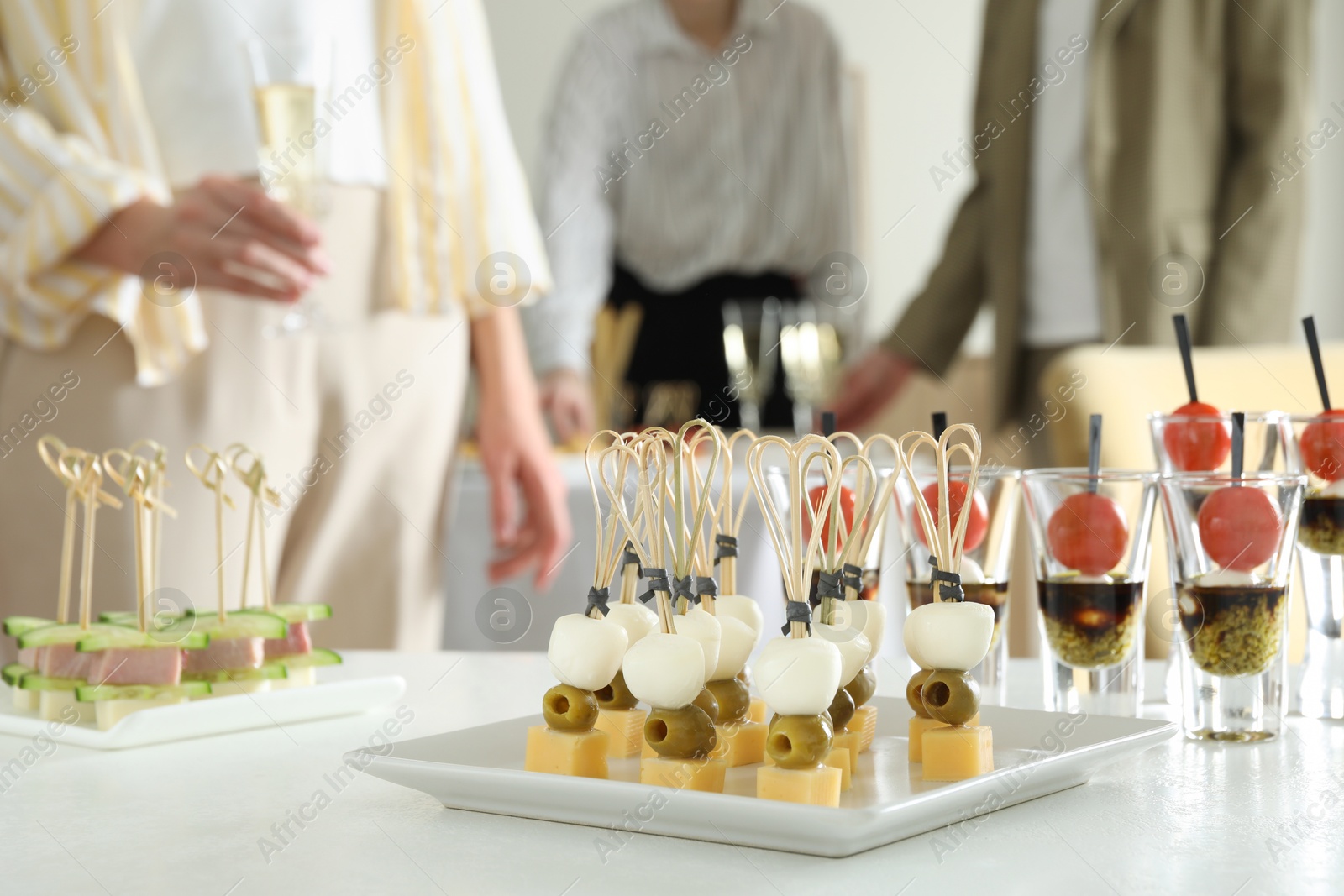 Photo of Many different tasty canapes on white table. People enjoying buffet meals indoors, closeup