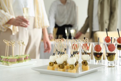 Photo of Many different tasty canapes on white table. People enjoying buffet meals indoors, closeup