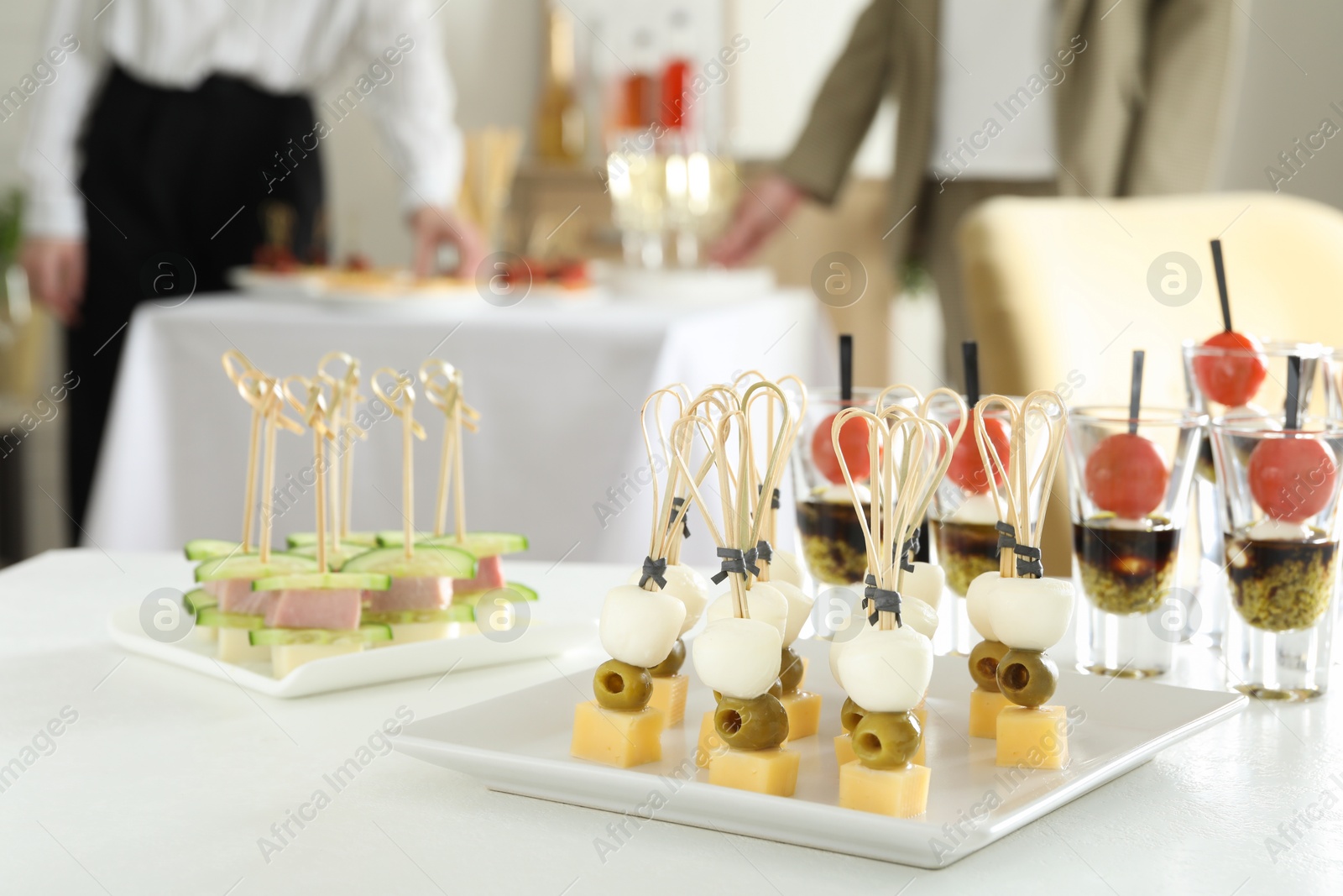 Photo of Many different tasty canapes on white table. People enjoying buffet meals indoors, closeup