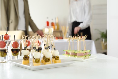 Photo of Many different tasty canapes on white table. People enjoying buffet meals indoors, closeup