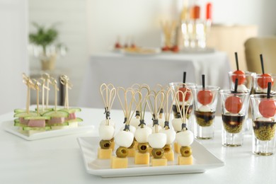 Photo of Many different tasty canapes on white table indoors