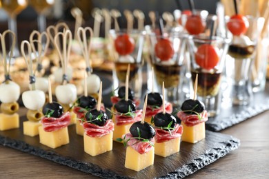 Photo of Many different tasty canapes on wooden table, closeup