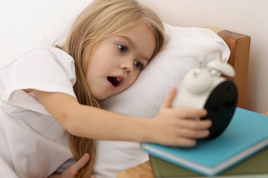 Photo of Overslept girl with alarm clock in bed at home