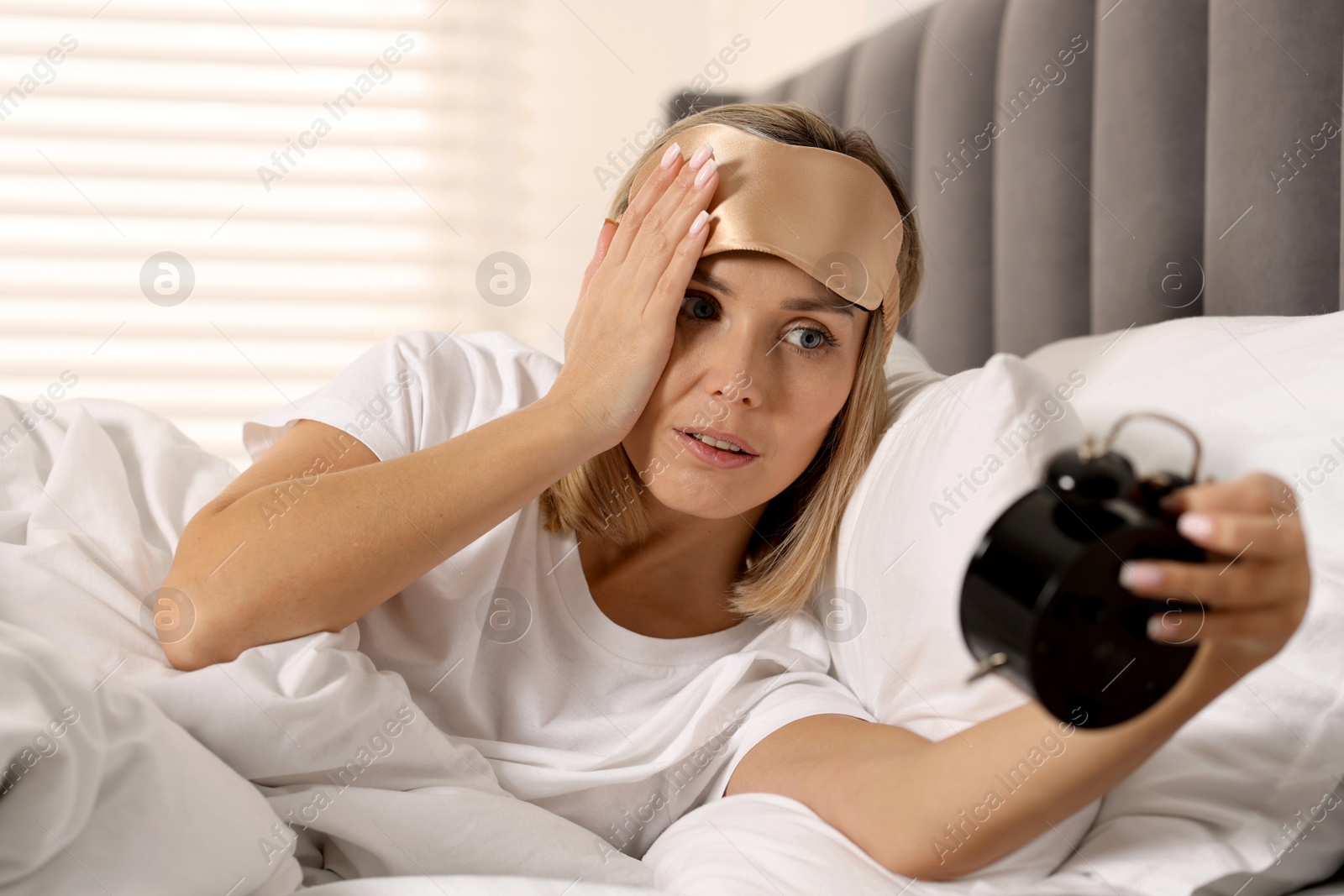 Photo of Overslept woman with alarm clock in bed at home