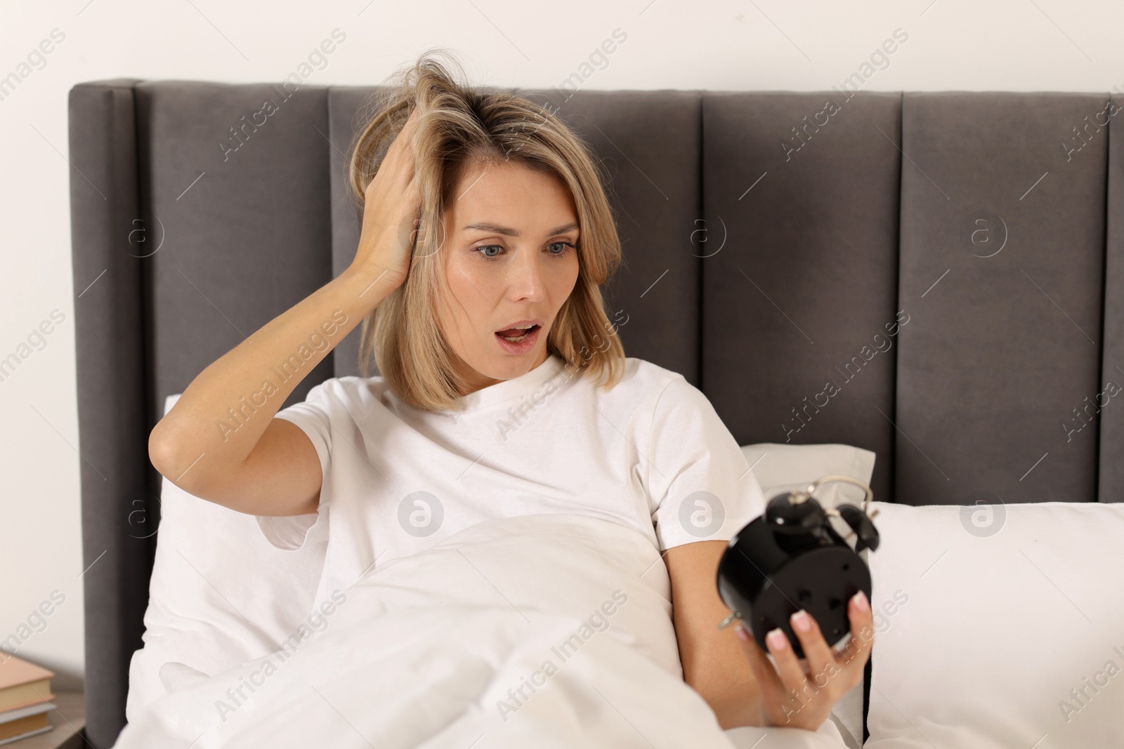 Photo of Overslept woman with alarm clock in bed at home