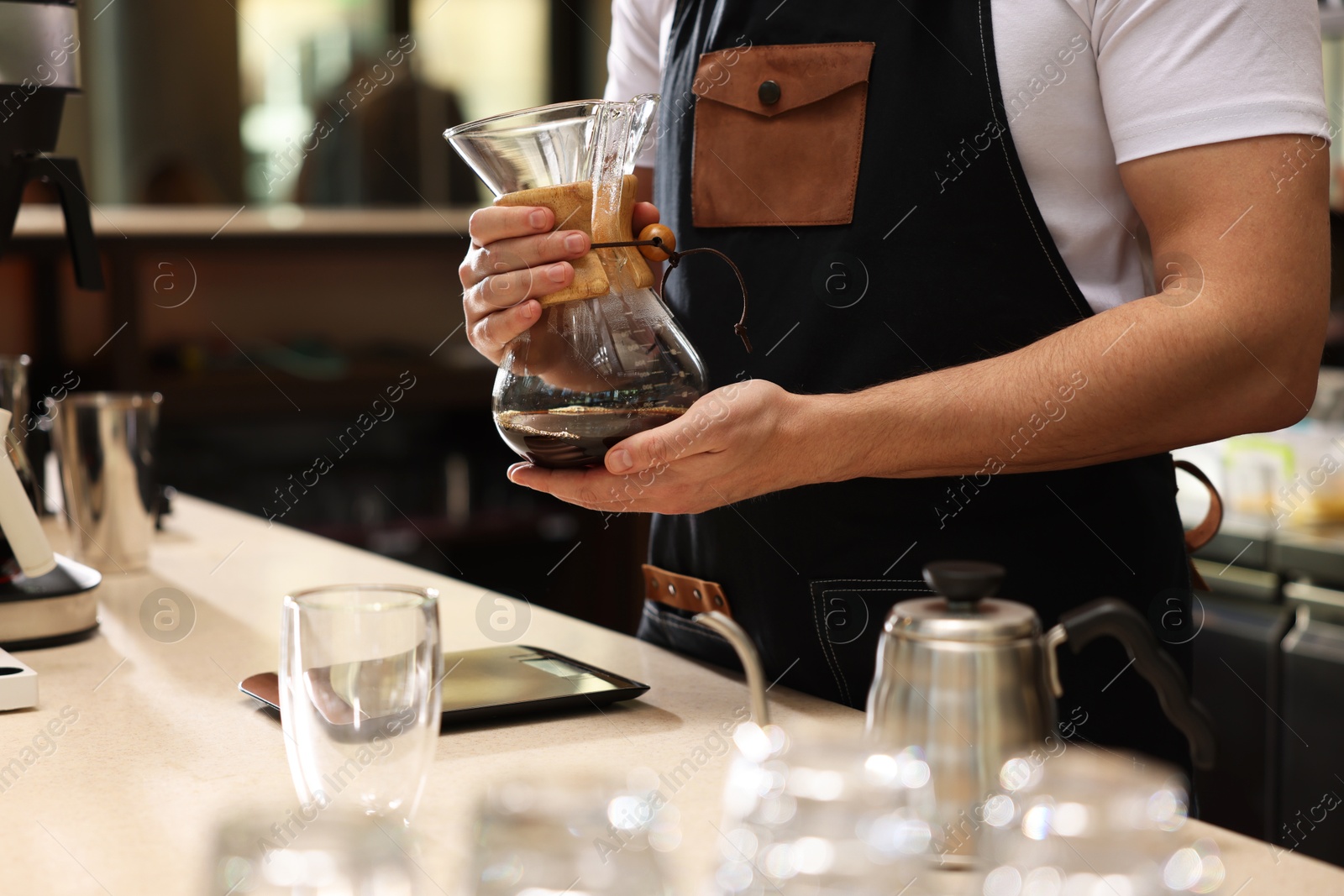 Photo of Barista with glass coffeemaker at table in cafe, closeup