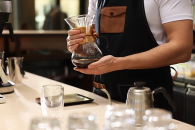 Photo of Barista with glass coffeemaker at table in cafe, closeup